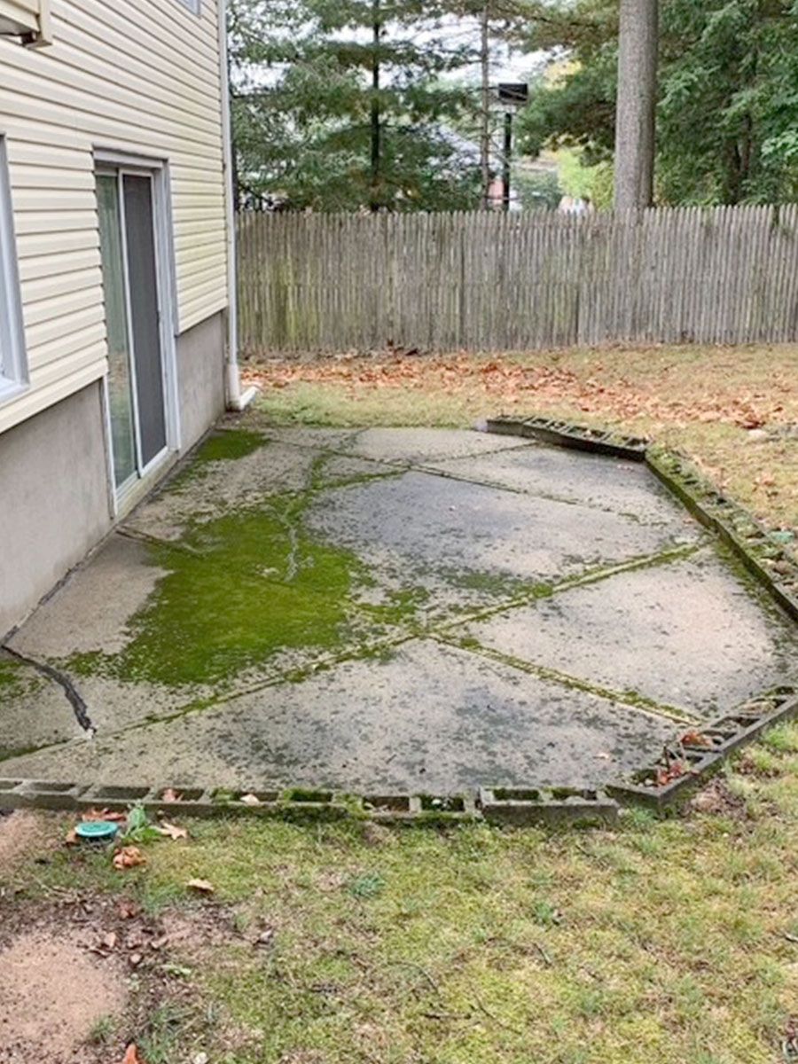 A broken patio with moss growing on it