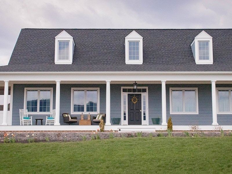 Blue house with white trim, dormer windows, and a porch.