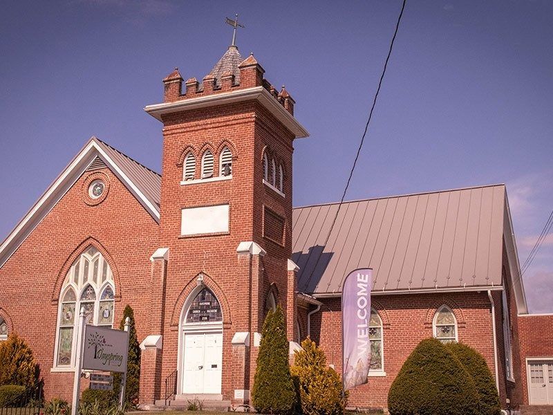 Red brick church with tower and welcome sign.