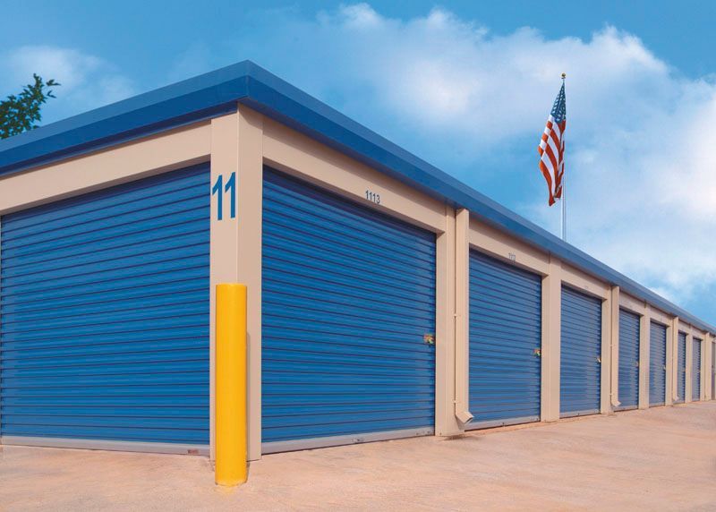 Storage units with blue doors, beige walls, and an American flag.