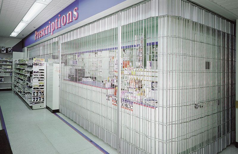 Accordion-style security gate in front of a pharmacy counter, labeled