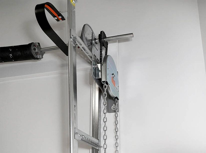 Garage door opener mechanism, metal frame, chain, and gears mounted on a white wall.