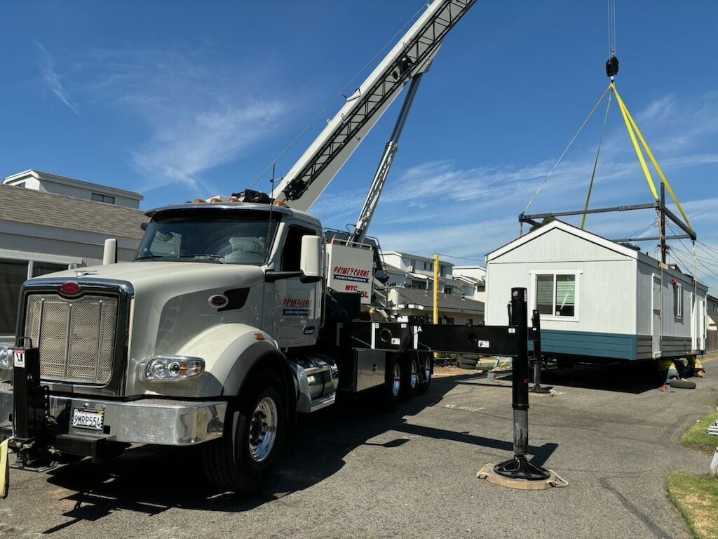 A truck with a crane attached to it is carrying a mobile home