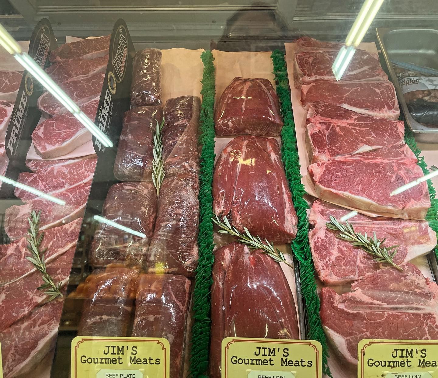 Display case filled with various cuts of raw red meat, labeled 