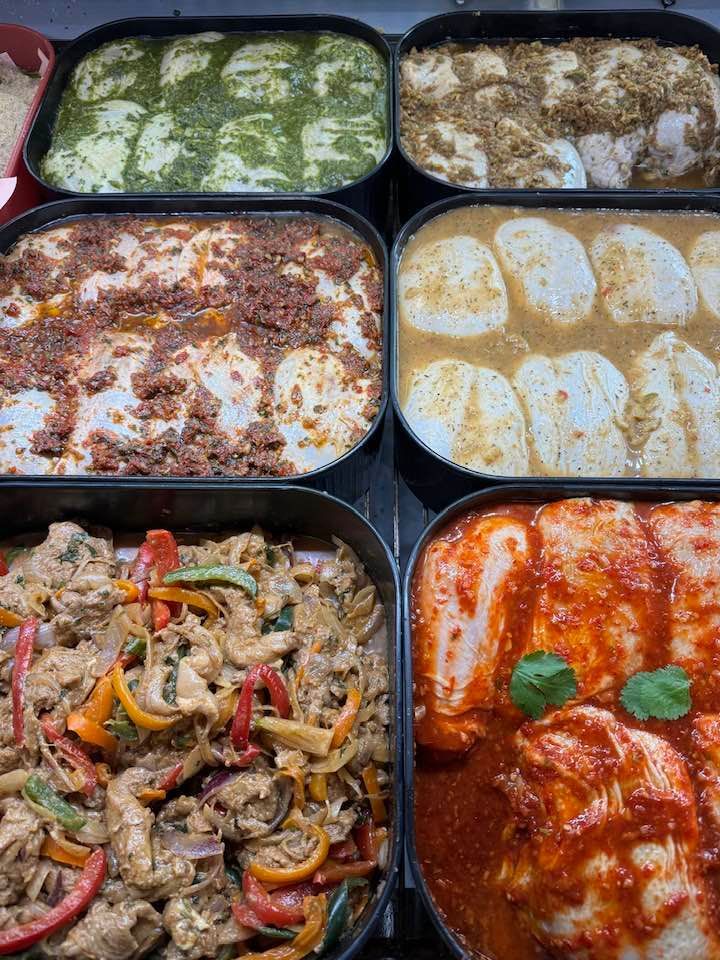 Overhead view of six food trays with assorted dishes like pasta, meat, and vegetables, in a variety of sauces.