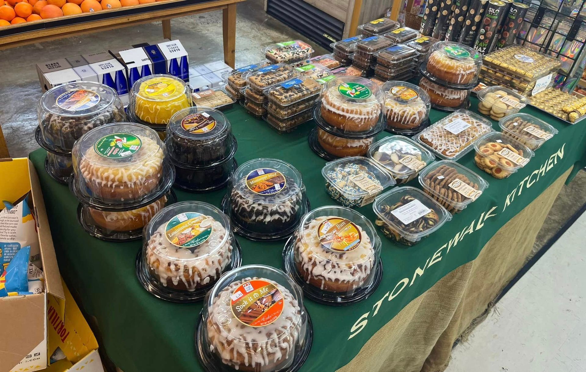 Cakes and pastries on display at a market, with a green tablecloth.