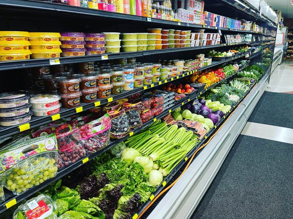 Produce aisle with packaged goods and fresh fruits and vegetables in a well-lit grocery store.