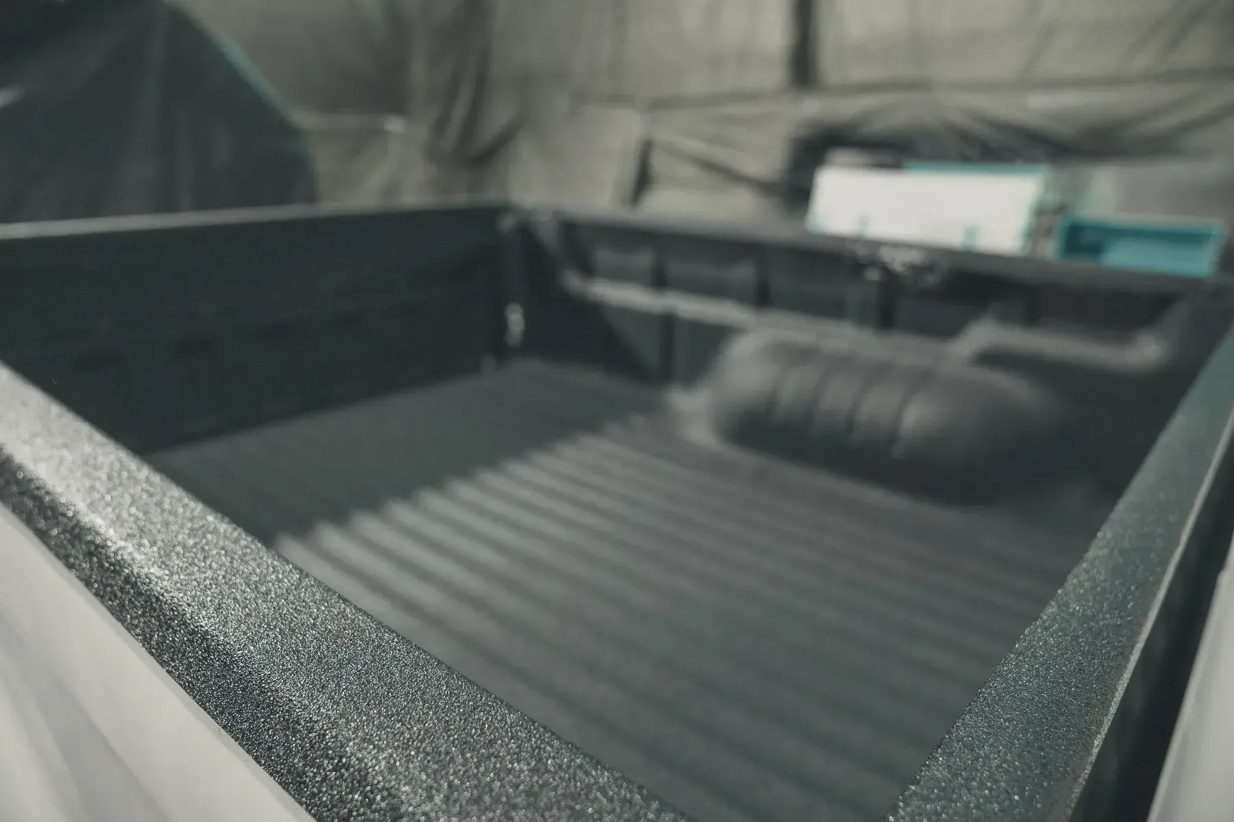 Truck bed coated in dark gray, textured bedliner.