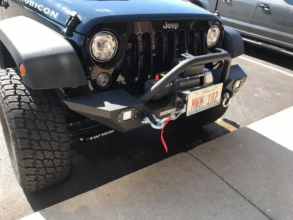 Black Jeep Wrangler Rubicon with aftermarket bumper and winch, parked outdoors.