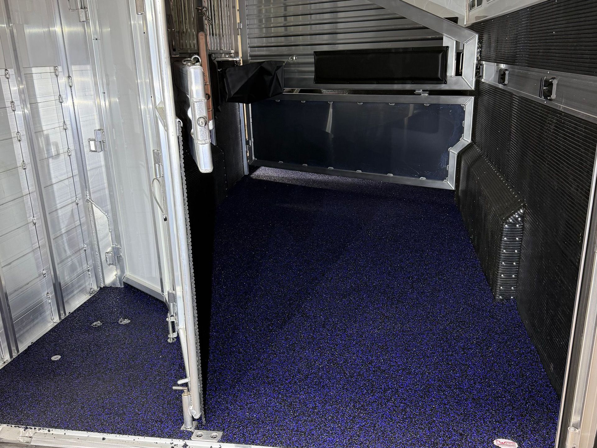 Interior of a metal livestock trailer with dark blue flooring and open side door