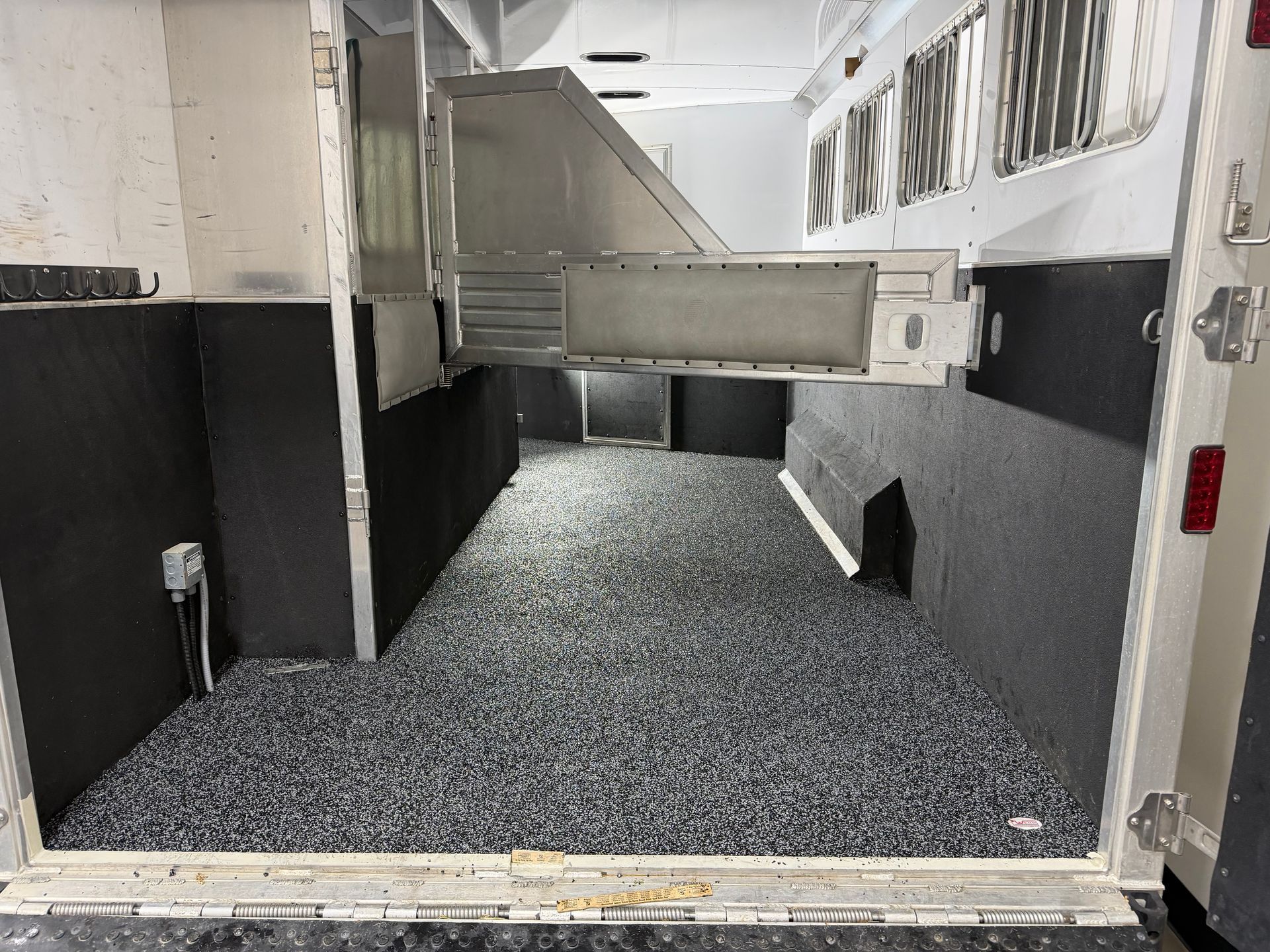 Empty industrial room with black-and-white walls and a metal duct overhead, floor covered in gray gravel.