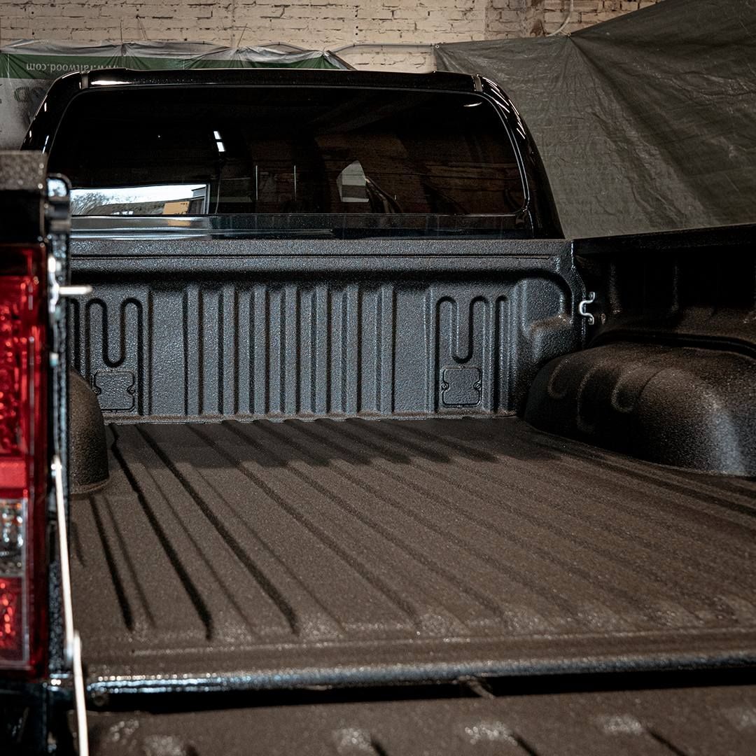 Black pickup truck bed with a bedliner and a camper shell.
