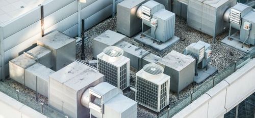 Rooftop HVAC units and vents on a light gray industrial building