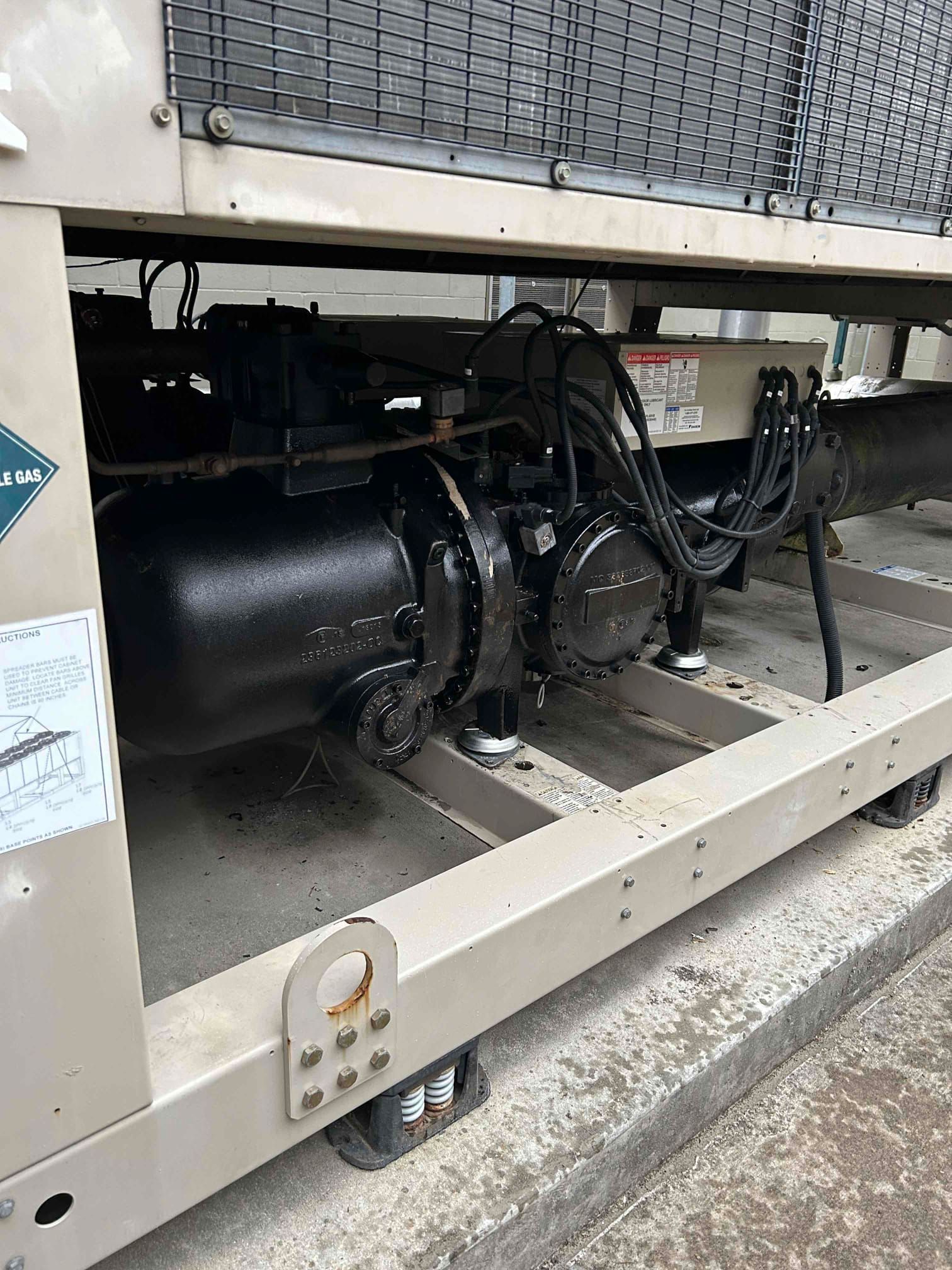 Black industrial machinery and cables inside a beige metal frame outdoors