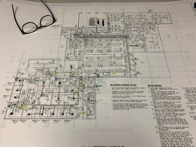 Architectural blueprint on a desk with glasses in the upper left corner