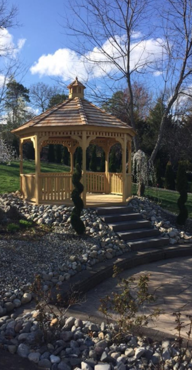 A wooden gazebo with stairs leading up to it in a park.