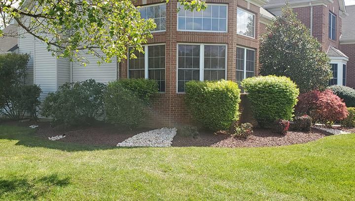 A brick house with a large lawn in front of it.
