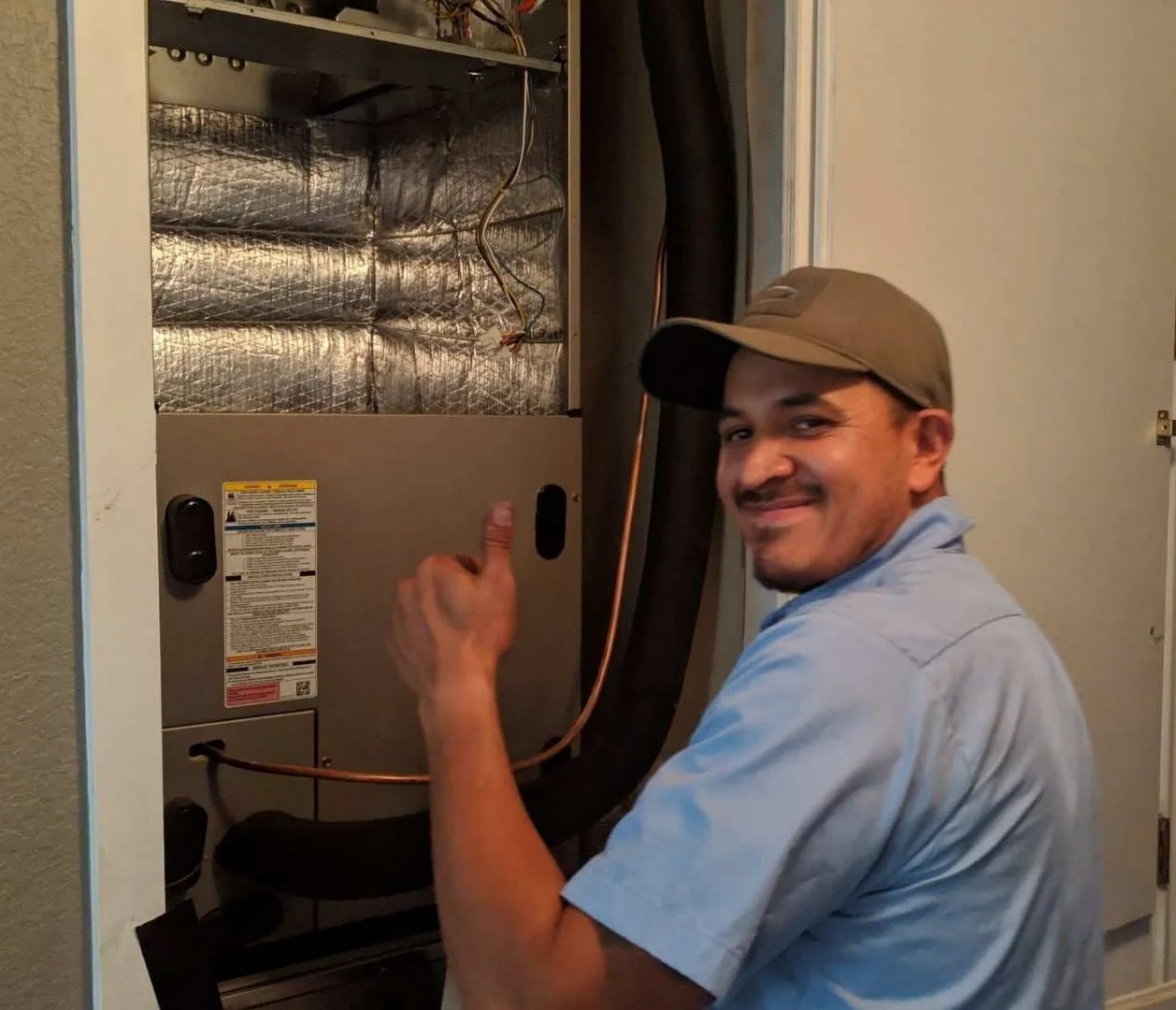 A man in a hat is working on an air conditioner