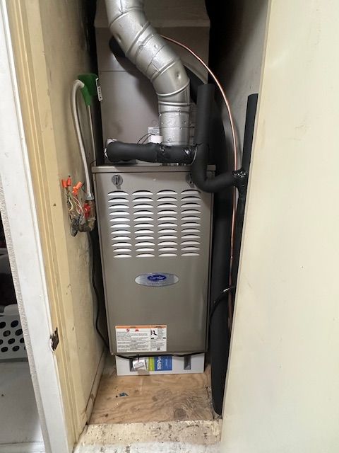 A furnace is sitting in a corner of a room next to a door.