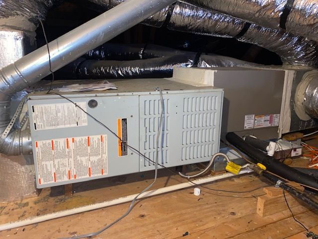 An air conditioner is sitting in the attic of a house.