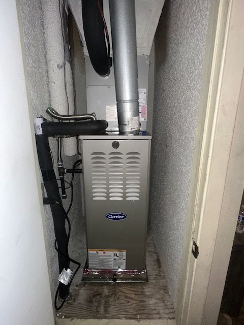 A furnace is sitting in a corner of a room next to a door.