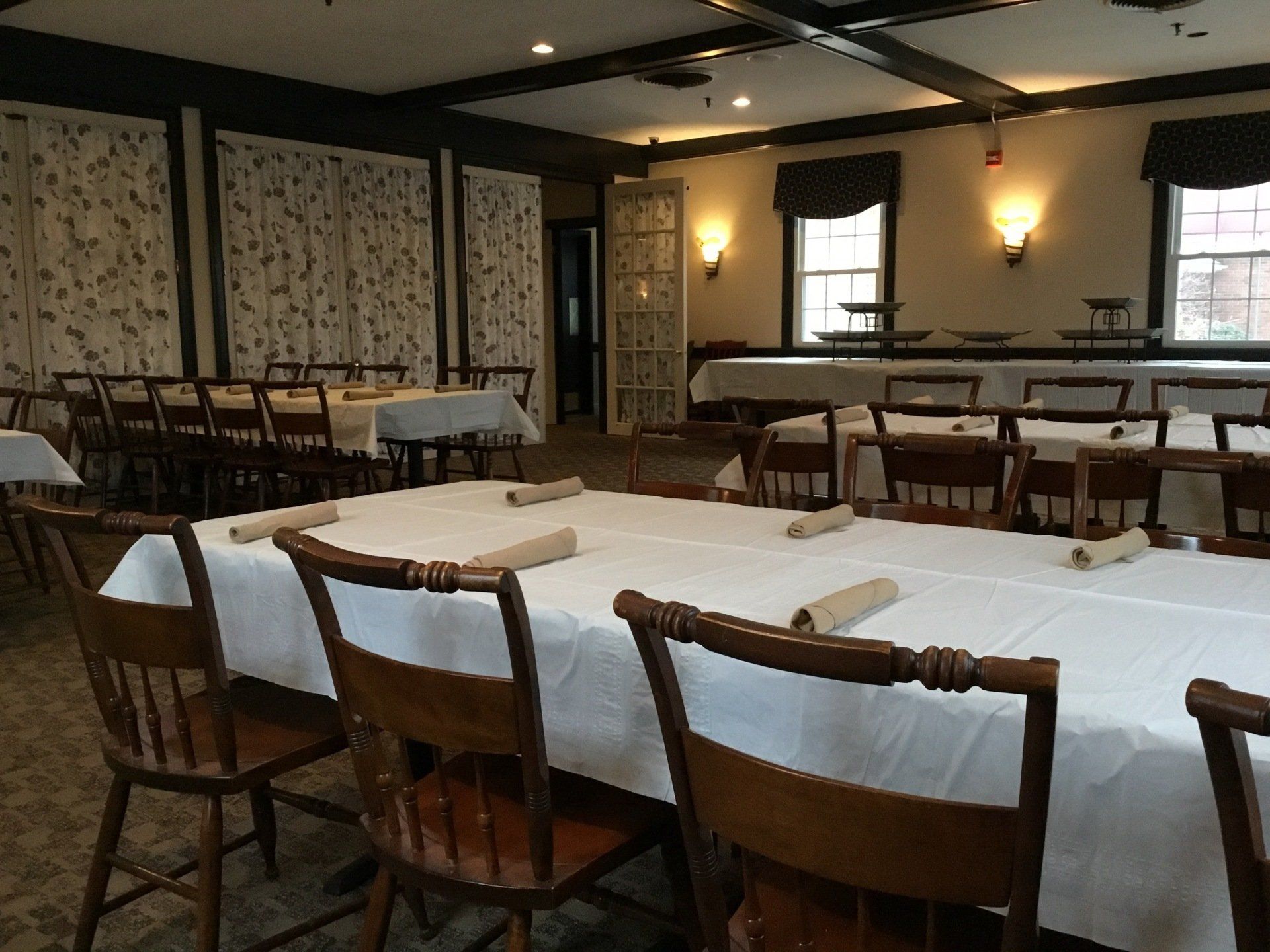 A dining room with tables and chairs with white tables cloths