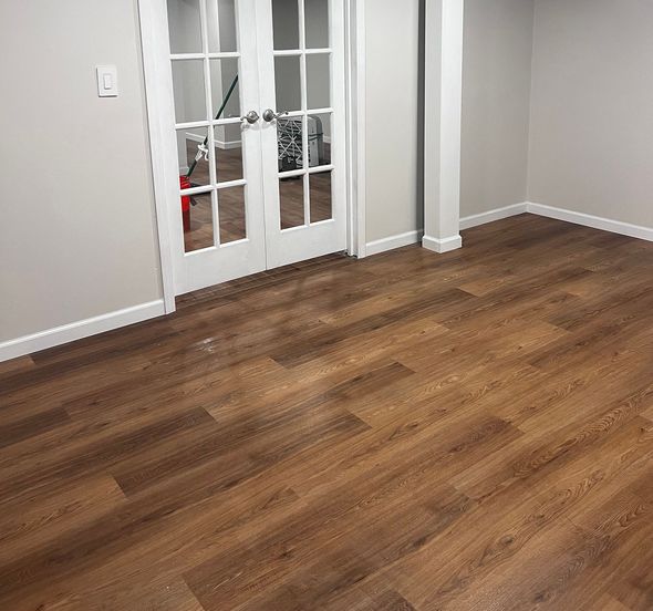 Wood-look flooring in a room with white trim and French doors. Pale gray walls.
