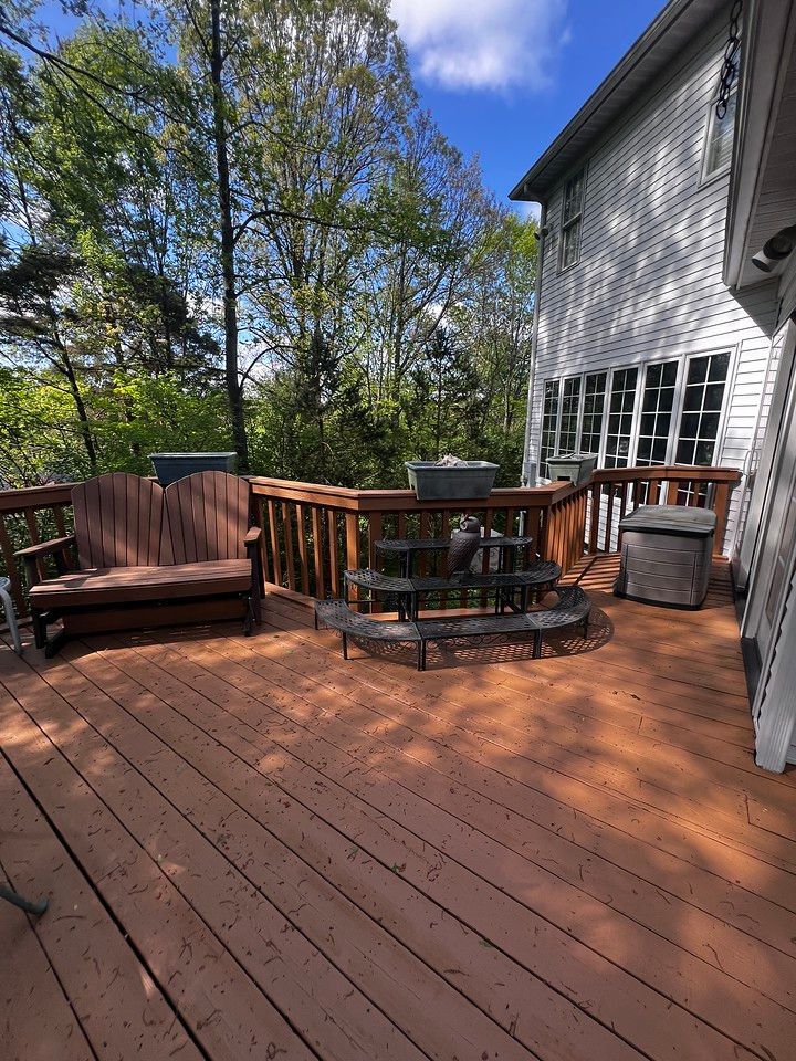 Wooden deck with brown furniture and a multi-tiered water fountain. House in background.