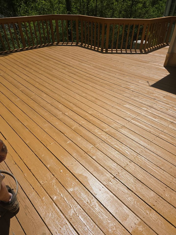 Wooden deck with light brown stain, railing, and a view of trees.