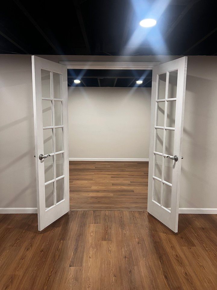 White French doors open to a room with wood floors and a black ceiling.
