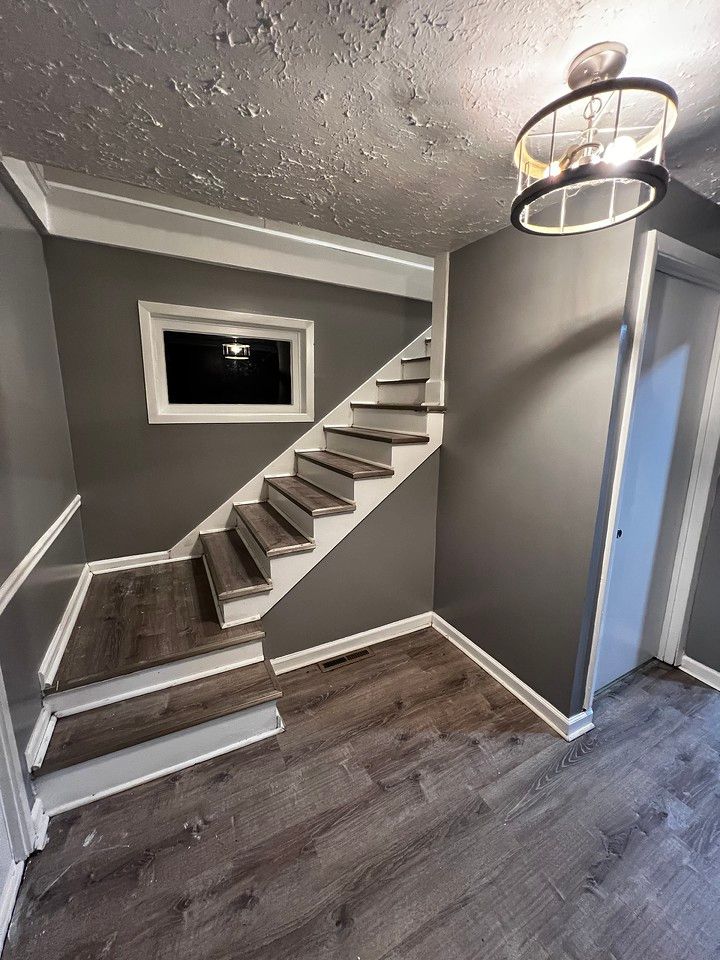 Gray stairway with wood-look steps, white trim, and a dark gray wall.