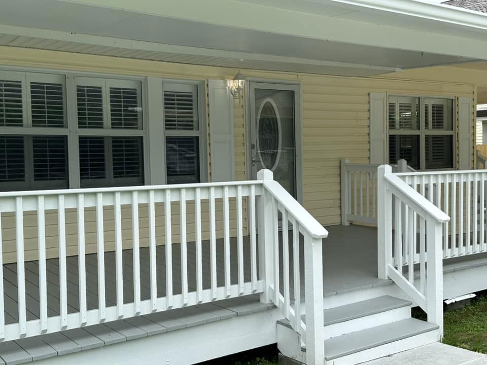A yellow house with a white porch and stairs