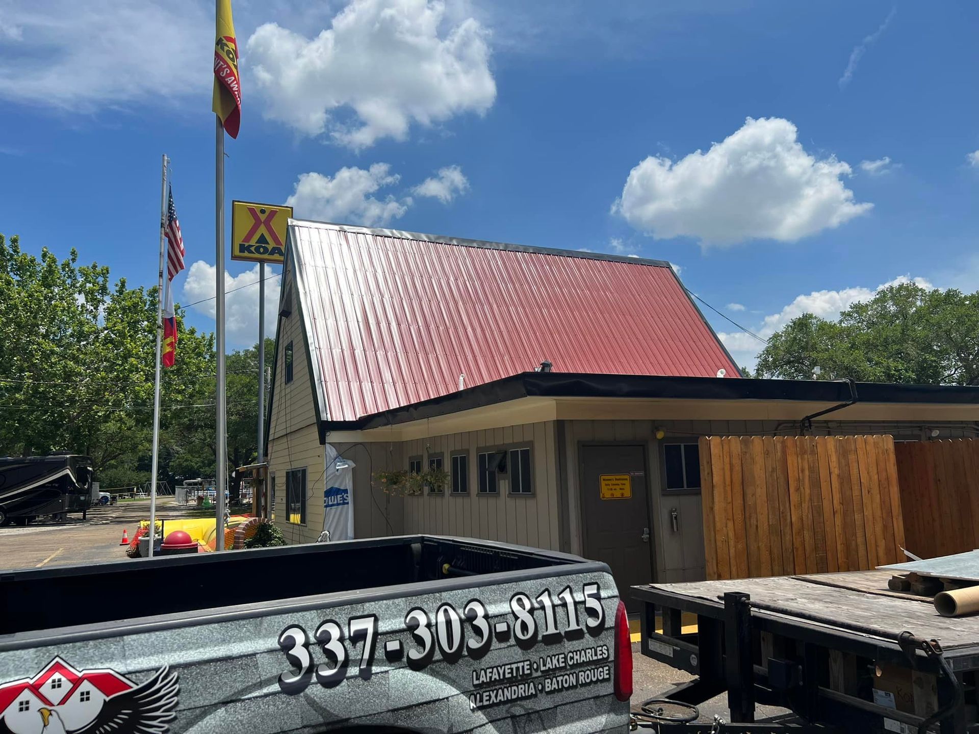 A truck is parked in front of a building with a red roof.