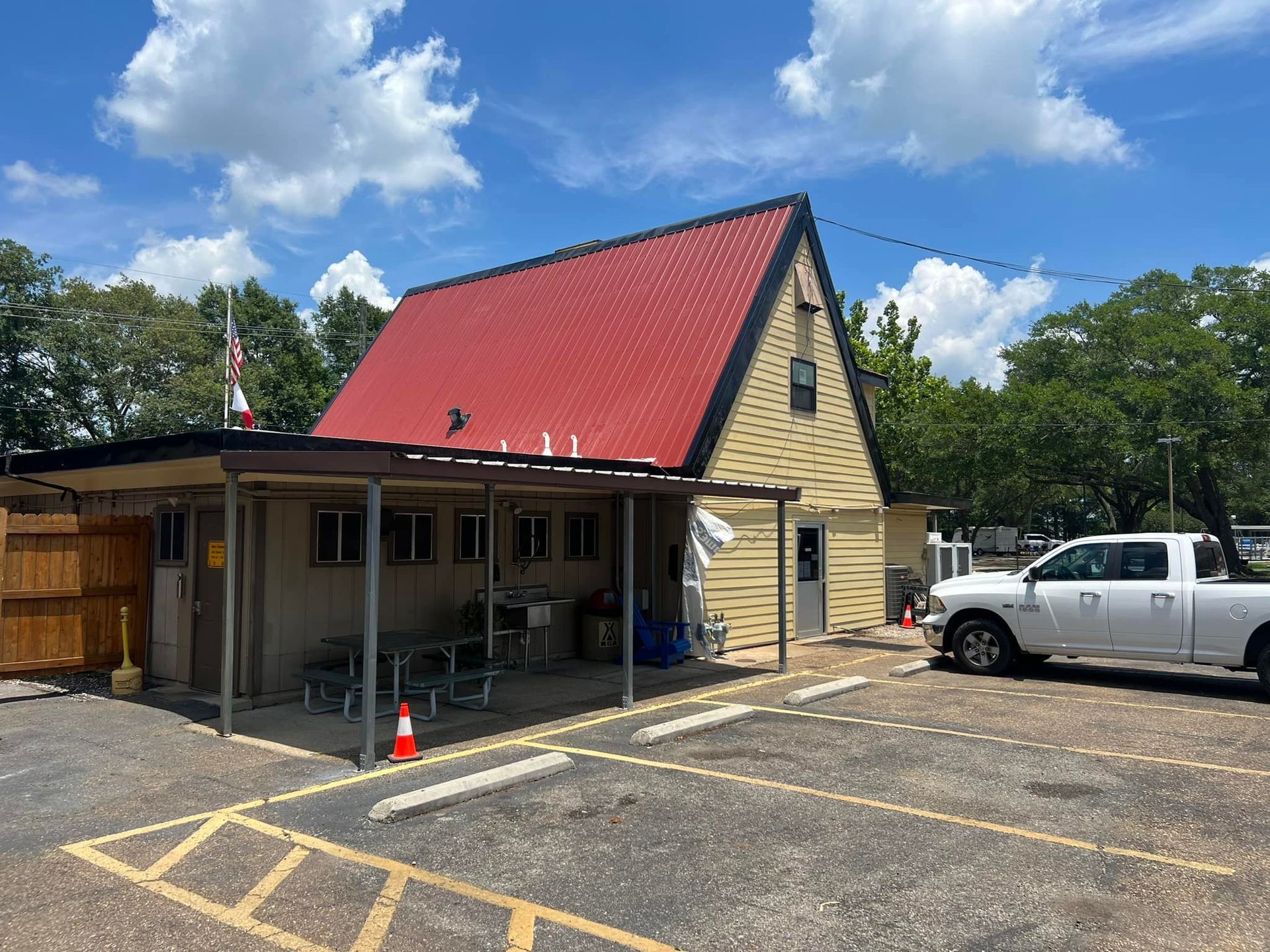 A white truck is parked in front of a building with a red roof.