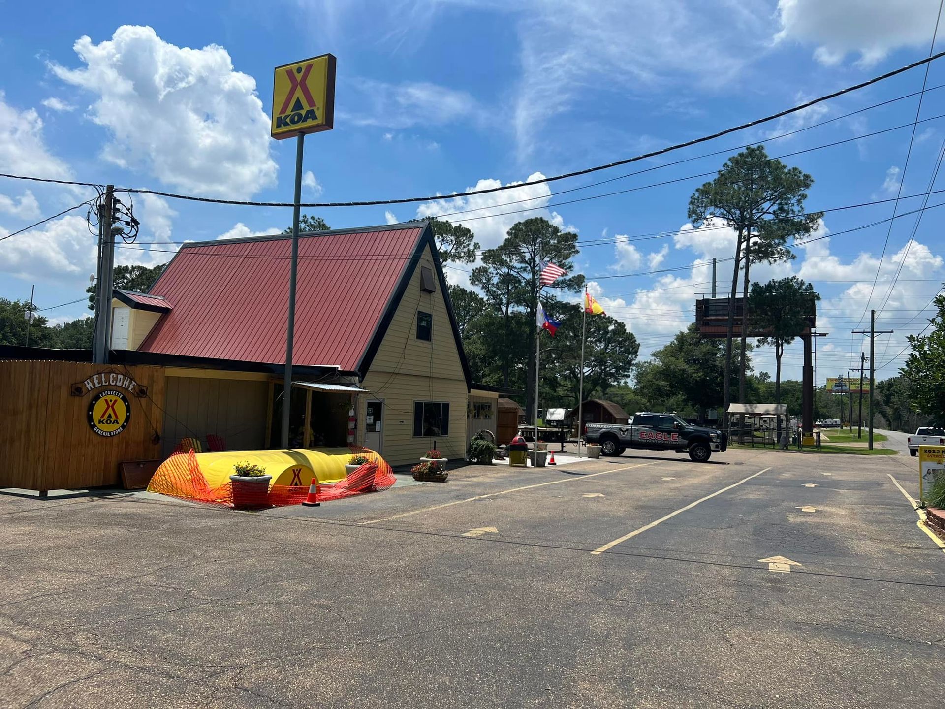 A large building with a red roof is sitting on the corner of a street.