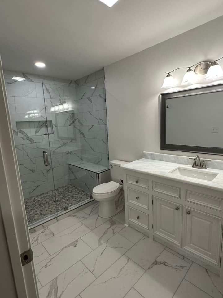 A bathroom with a toilet , sink , shower and mirror.