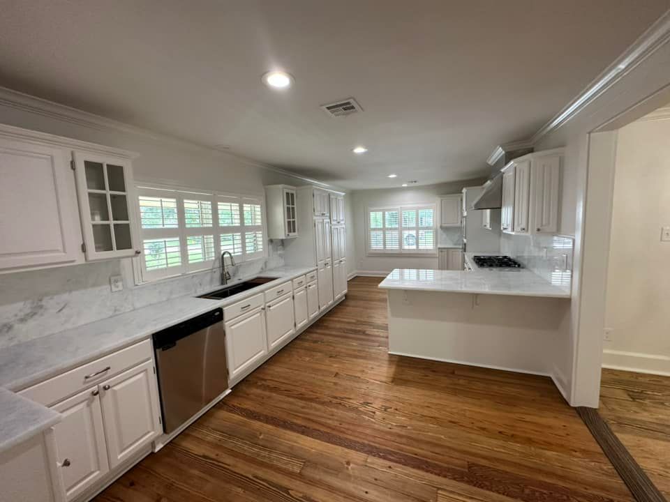 A kitchen with white cabinets , stainless steel appliances , and hardwood floors.
