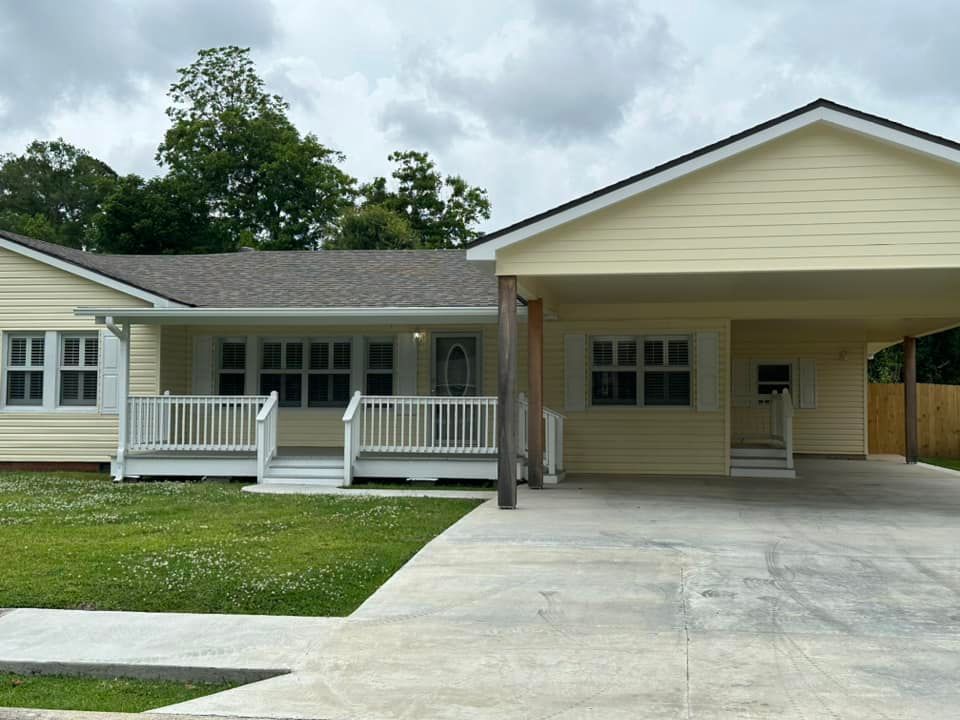A yellow house with a carport and a porch