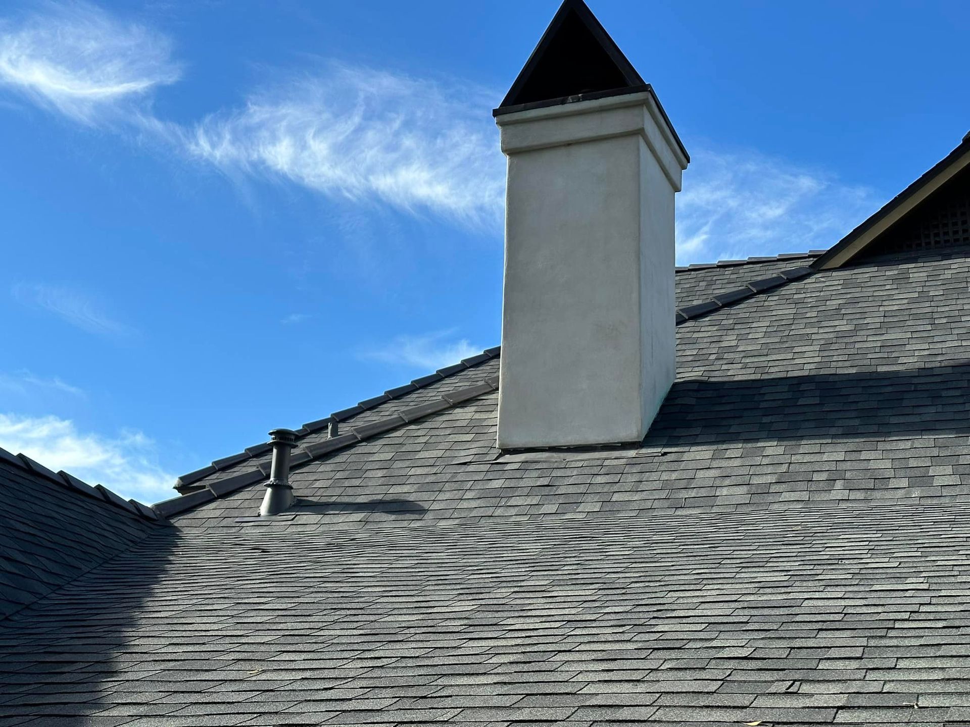 A chimney on top of a roof with a blue sky in the background