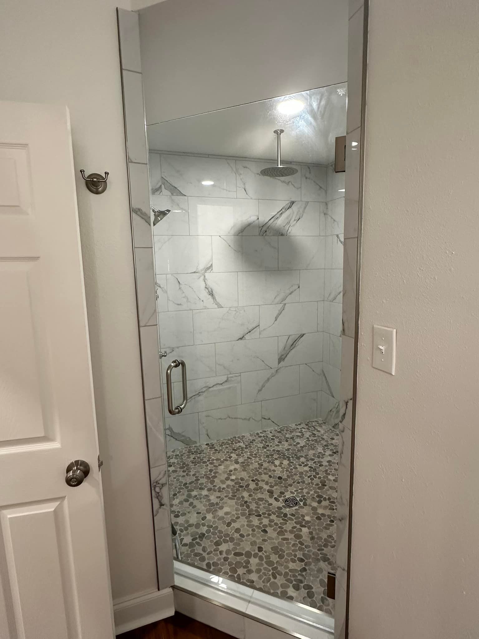 A bathroom with a walk in shower with a glass door.
