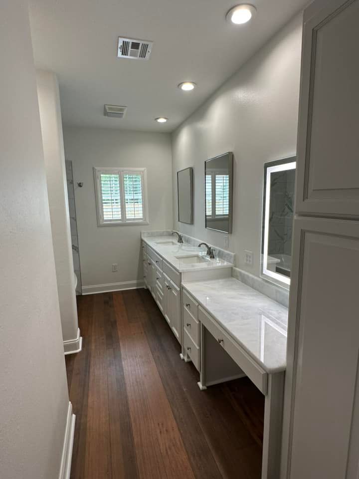 A bathroom with two sinks , two mirrors and hardwood floors.