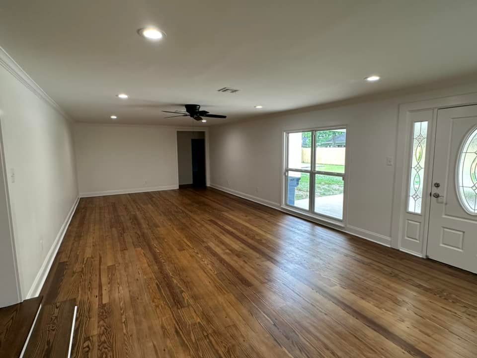 An empty living room with hardwood floors and a ceiling fan.