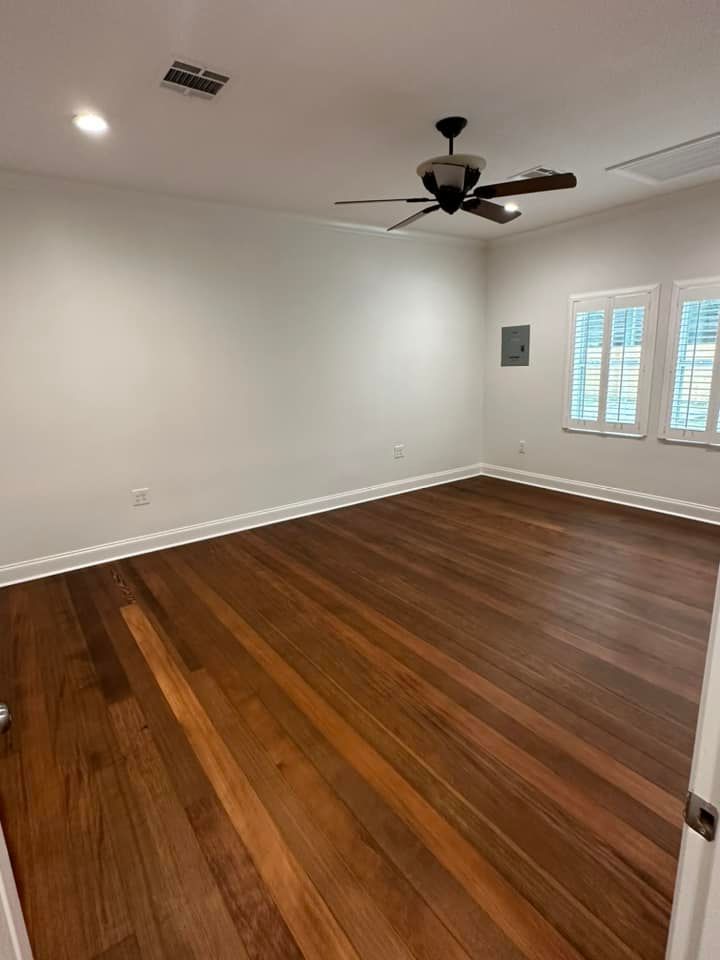 An empty room with hardwood floors and a ceiling fan.