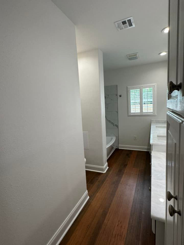 A bathroom with hardwood floors and white walls.