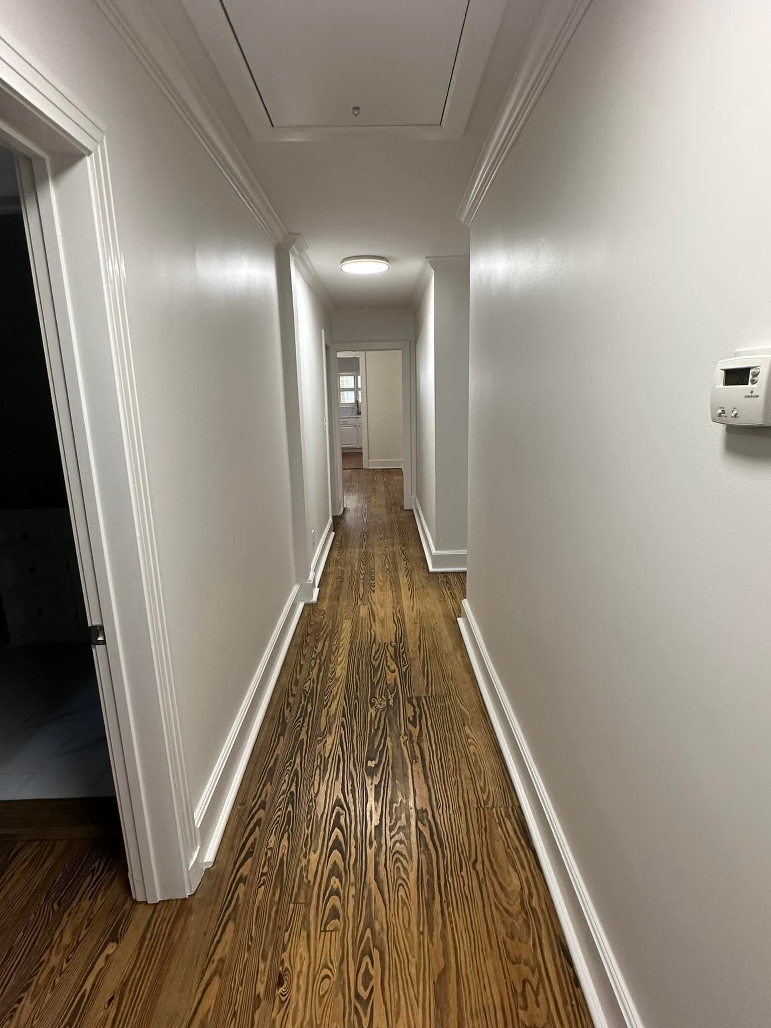 A long hallway with wooden floors and white walls.
