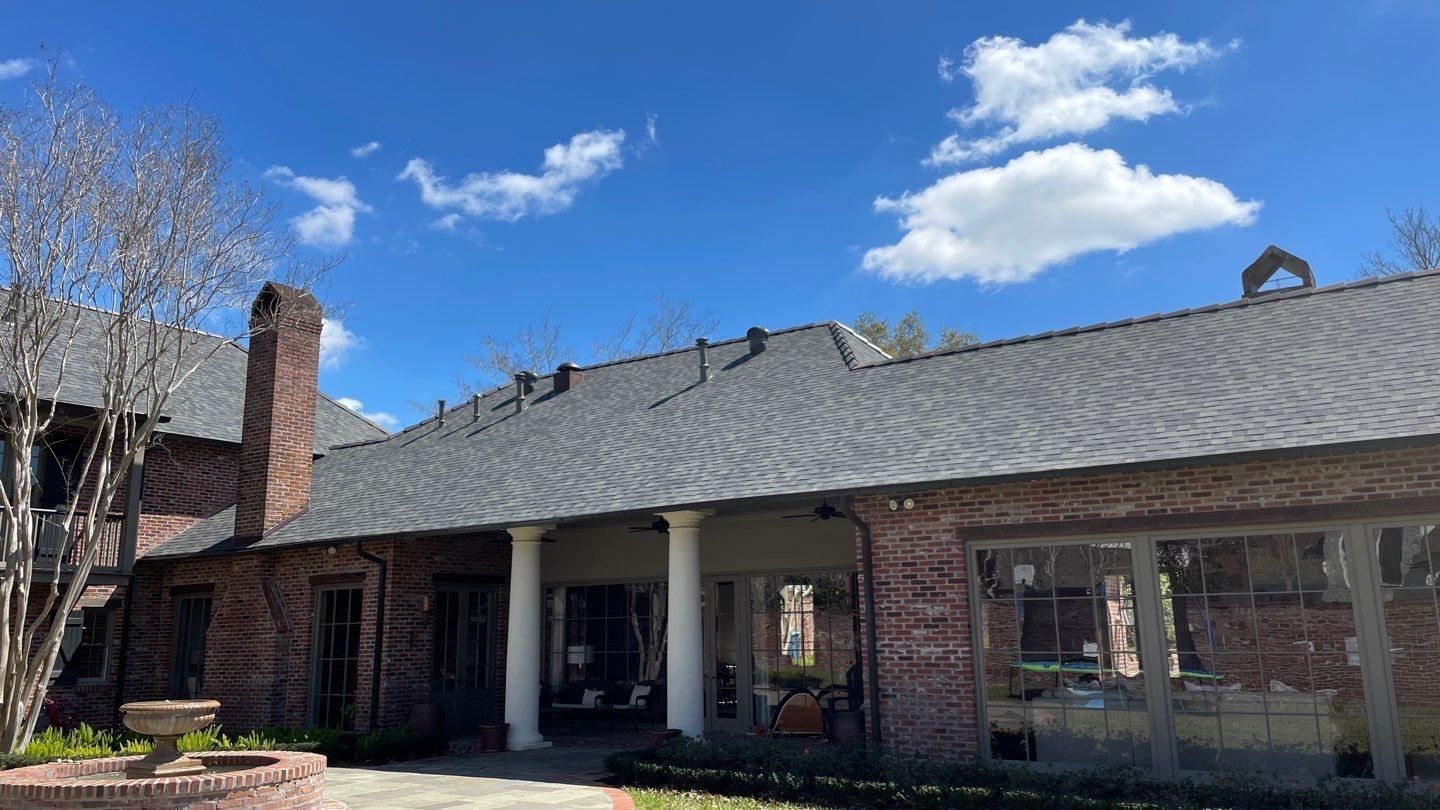 A large brick building with a gray roof and a lot of windows.