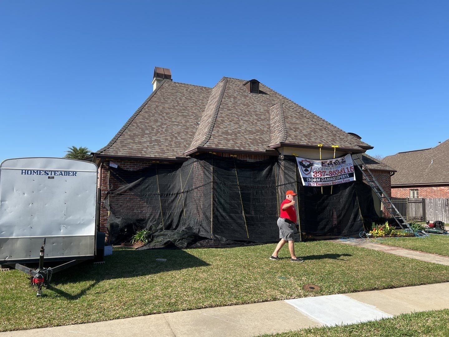 A woman is walking in front of a house covered in tarps.