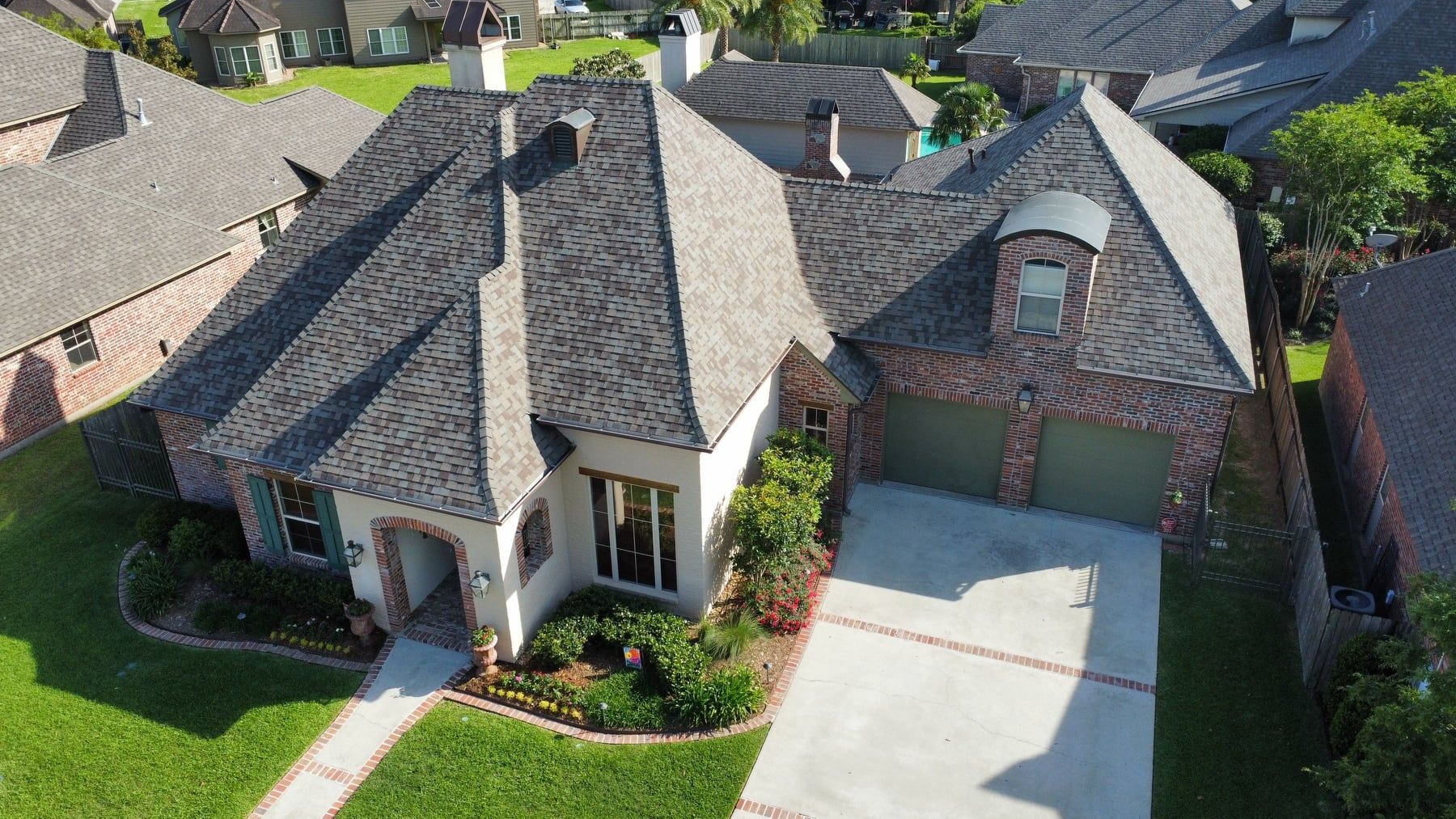 An aerial view of a house with a black roof and a green garage door.