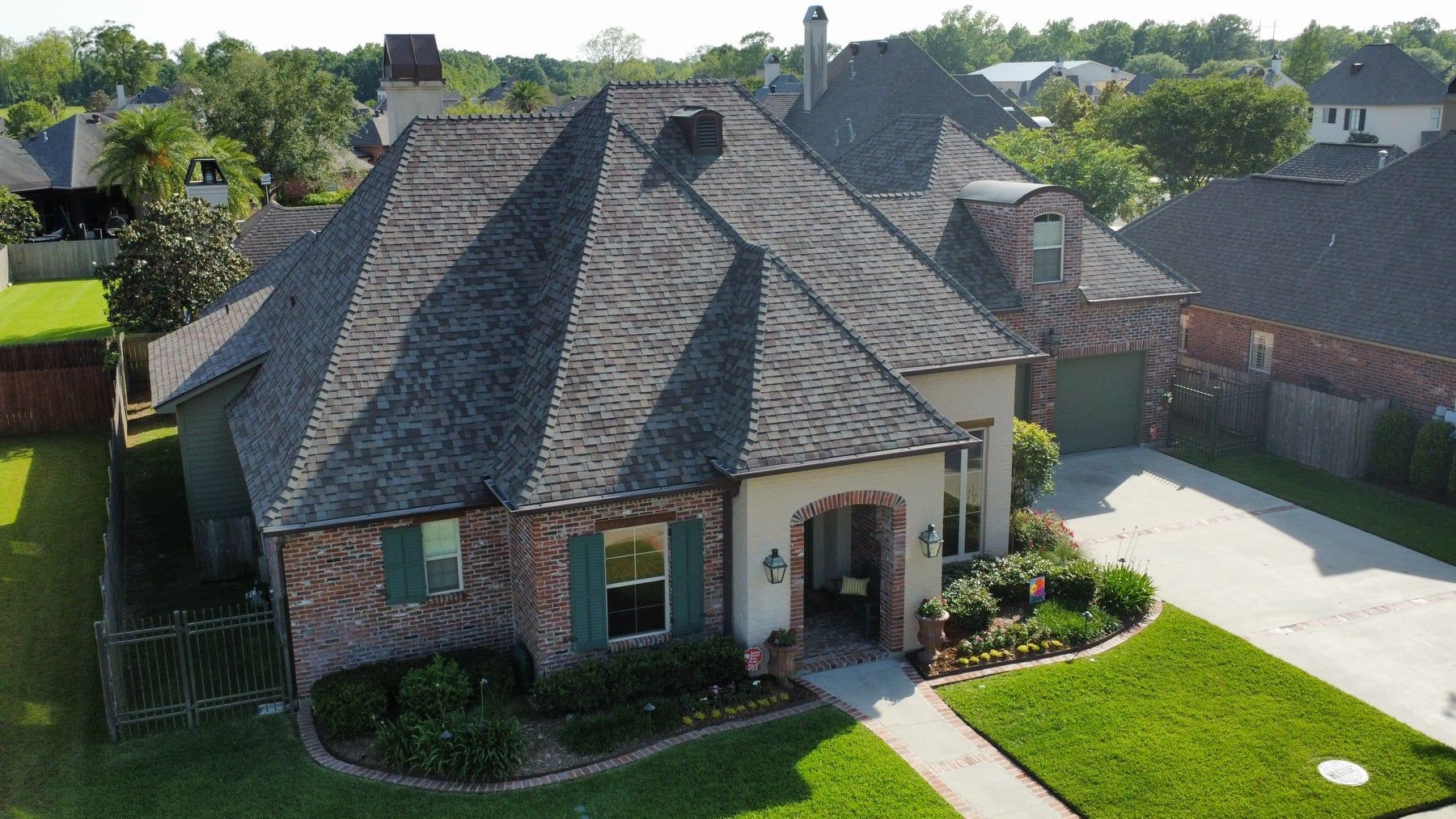 An aerial view of a large brick house with a gray roof.
