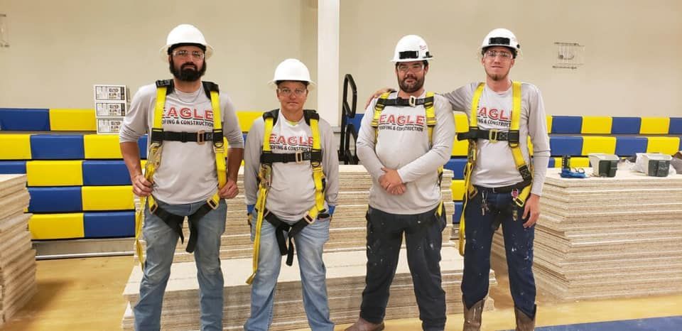 A group of construction workers wearing hard hats and safety vests are posing for a picture.